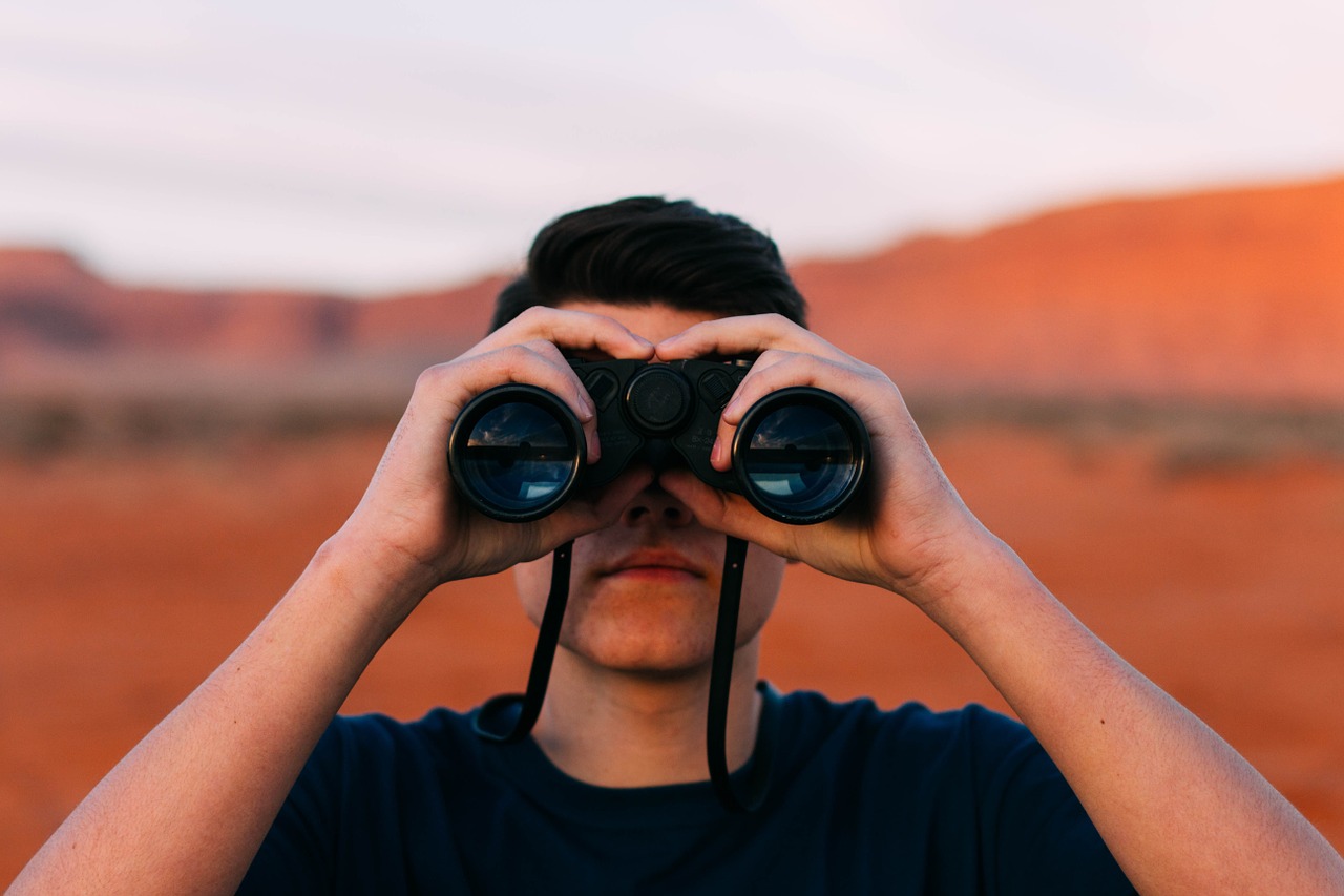 uomo con binocolo nel deserto
